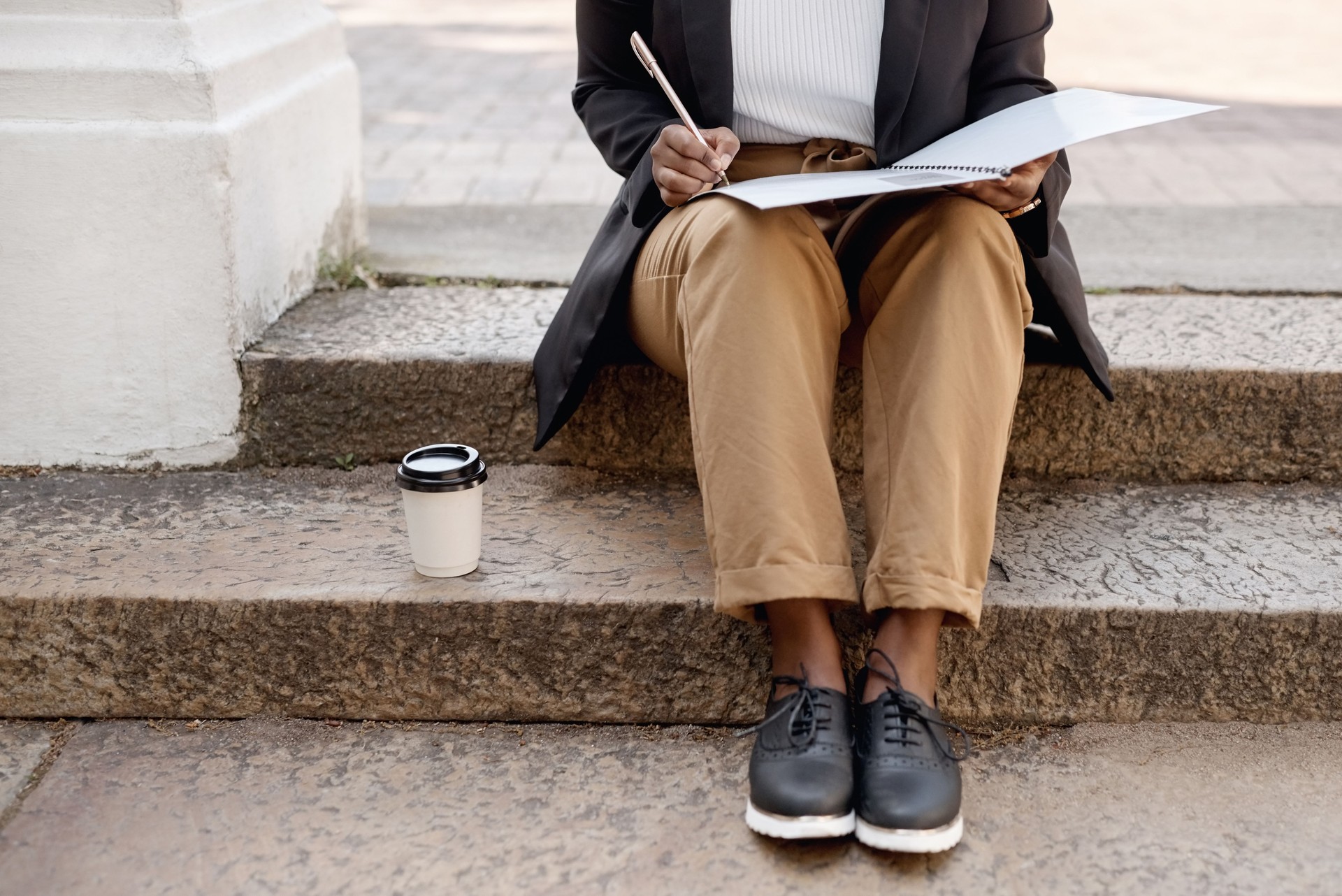 Closeup shot of an unrecognisable businesswoman going through paperwork while sitting on a staircase outdoors